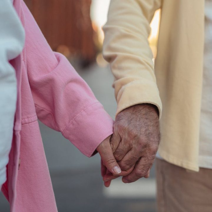 Close view of senior couple holding hands, symbolizing love and companionship.